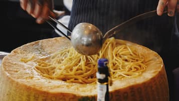 A large wheel of cheese with a ladle of spaghetti on top.