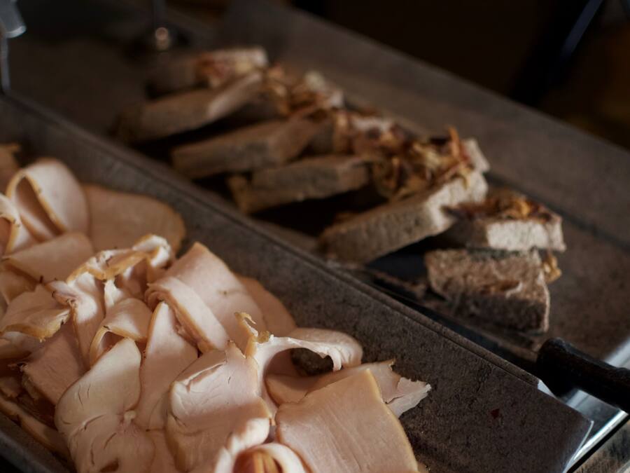 Een presentatie van plakjes kalkoen en brood bij een bedieningsbalie.