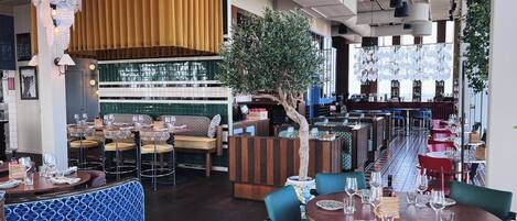 A restaurant with booths, round tables, and a bar area.