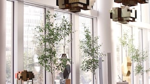 A modern interior with large windows, a sectional sofa, a coffee table, and geometric pendant lighting.