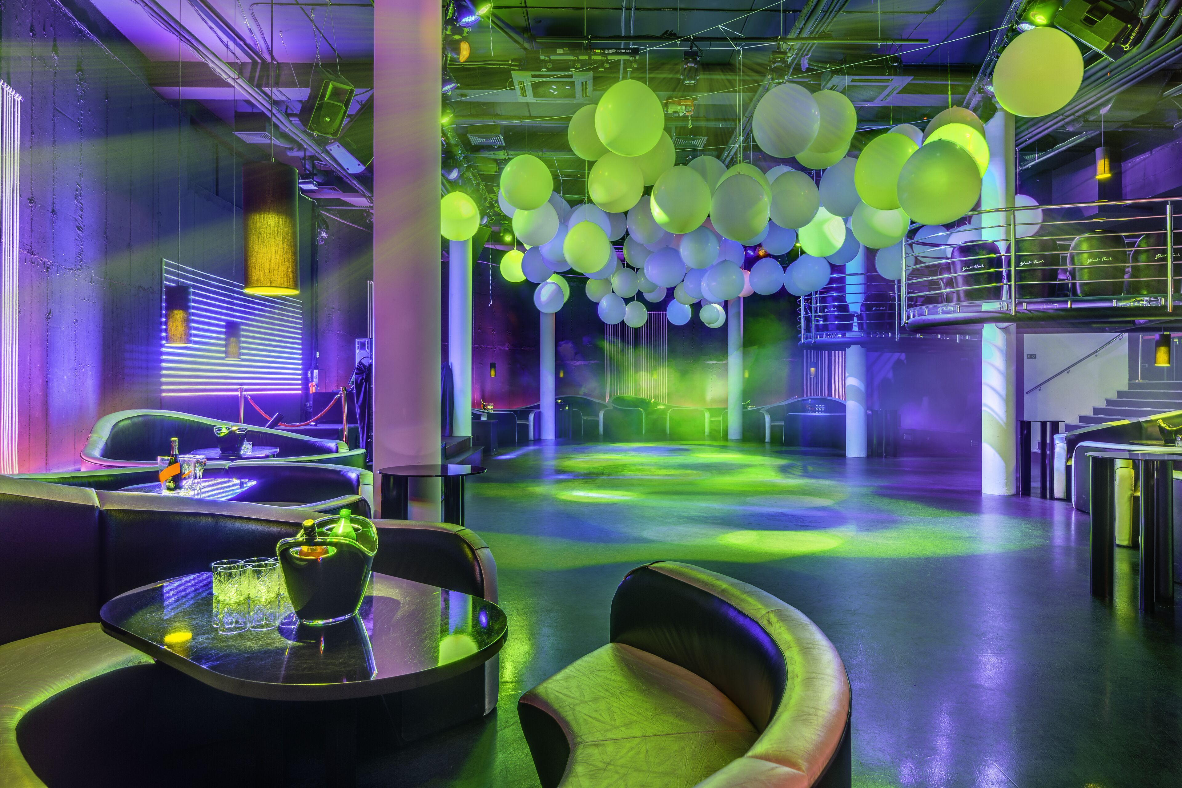 Un espace lounge moderne, doté de sièges, de tables et d’un plafond orné de luminaires sphériques suspendus.