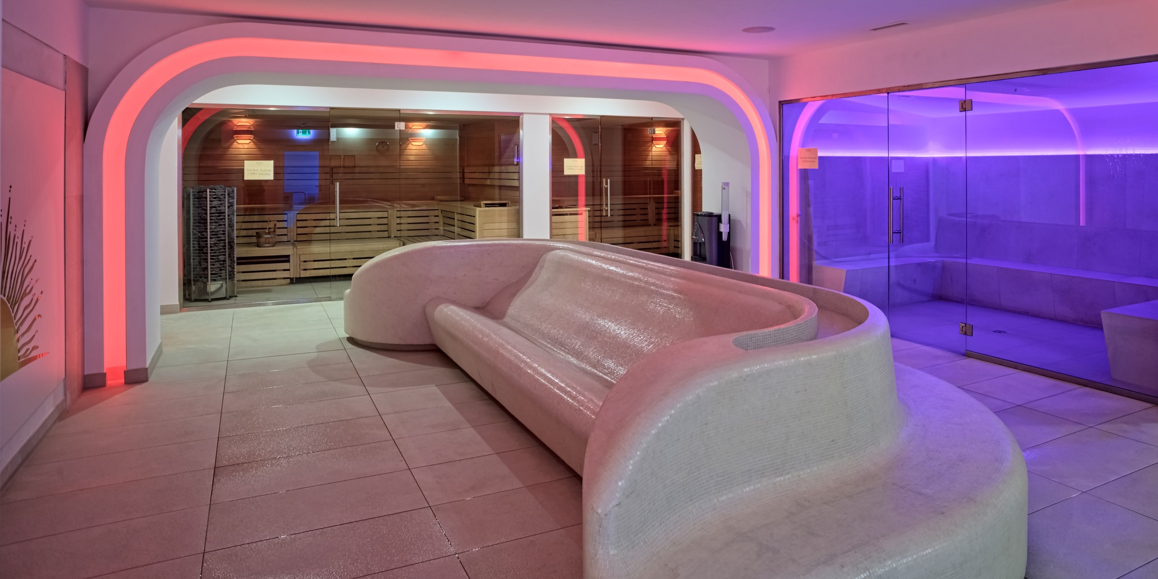 A modern spa area with a large, curved bench and a glass-enclosed sauna.