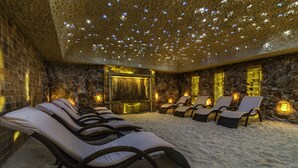 A spa area with stone walls, a stone floor, and multiple lounge chairs. - Grand Lubicz - Uzdrowisko Ustka (Ustka)