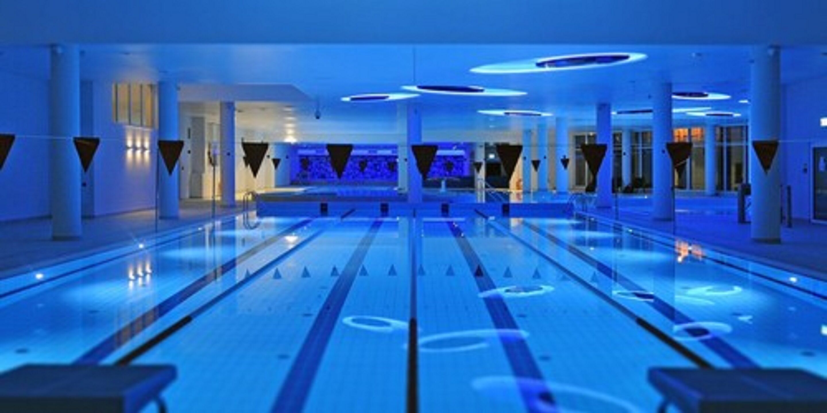 A spacious indoor area with a long, narrow pool and multiple seating areas.