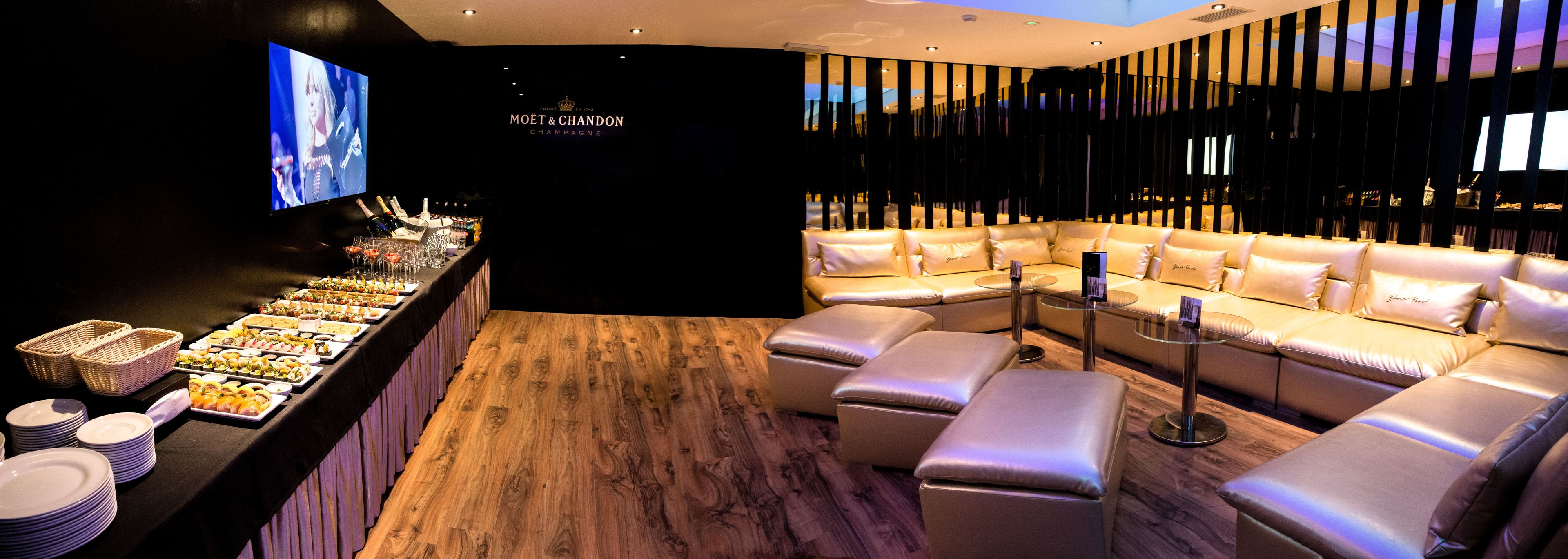 A luxurious lounge area with a bar, seating, and a television screen.