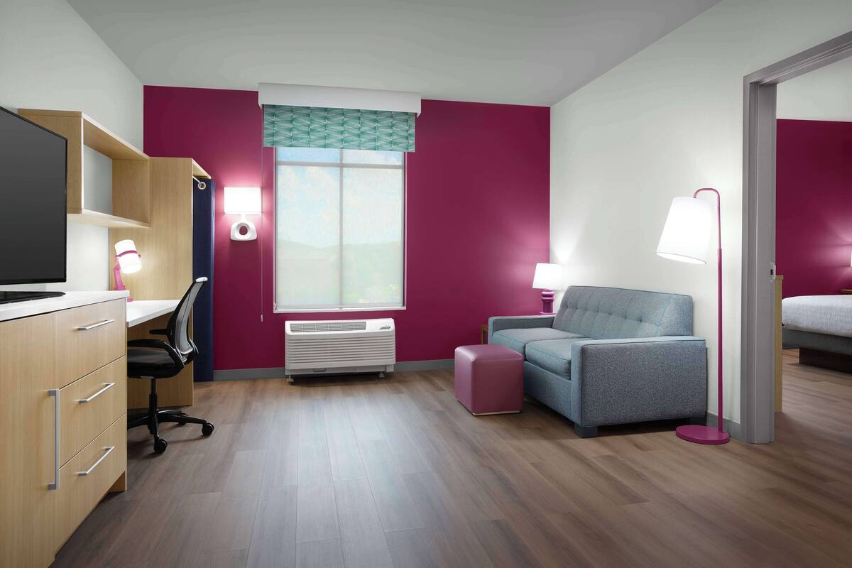 Ein Hotelzimmer mit Schreibtisch, Stuhl, Bett und einem Fenster mit Blick.