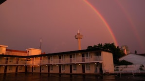 Um motel com estrutura em dois andares, uma torre central e um arco-íris visível.