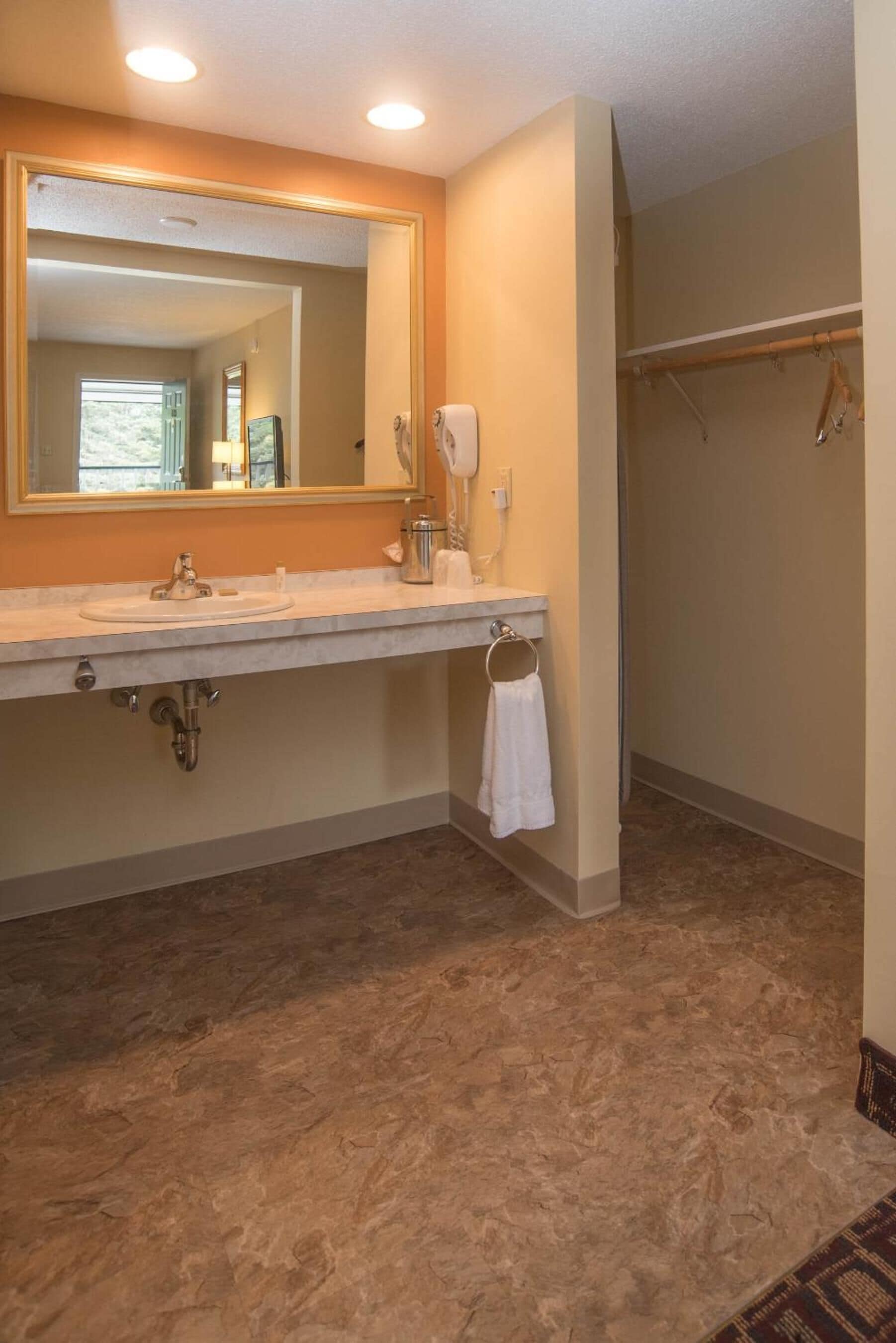 A bathroom with a large mirror, a sink, a towel rack, and a shower area.