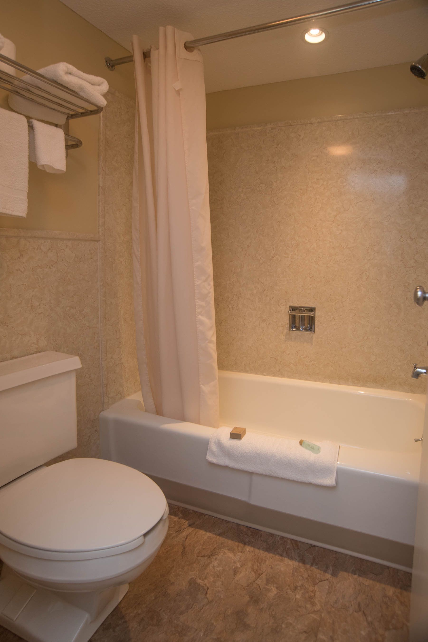 Une salle de bain équipée de toilettes, d’une baignoire et d’un rideau de douche.