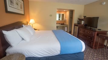 Habitación de hotel con cama, televisión, cómoda y baño visible a través de una puerta abierta.