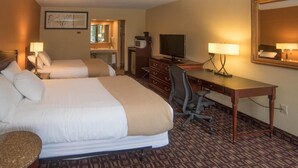 A hotel room with two beds, a desk with a computer, a chair, a TV, and a mirror.