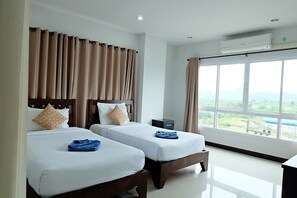 A hotel room with two beds, a large window with a view, and an air conditioning unit. - Krabi Hipster Hotel (Krabi)
