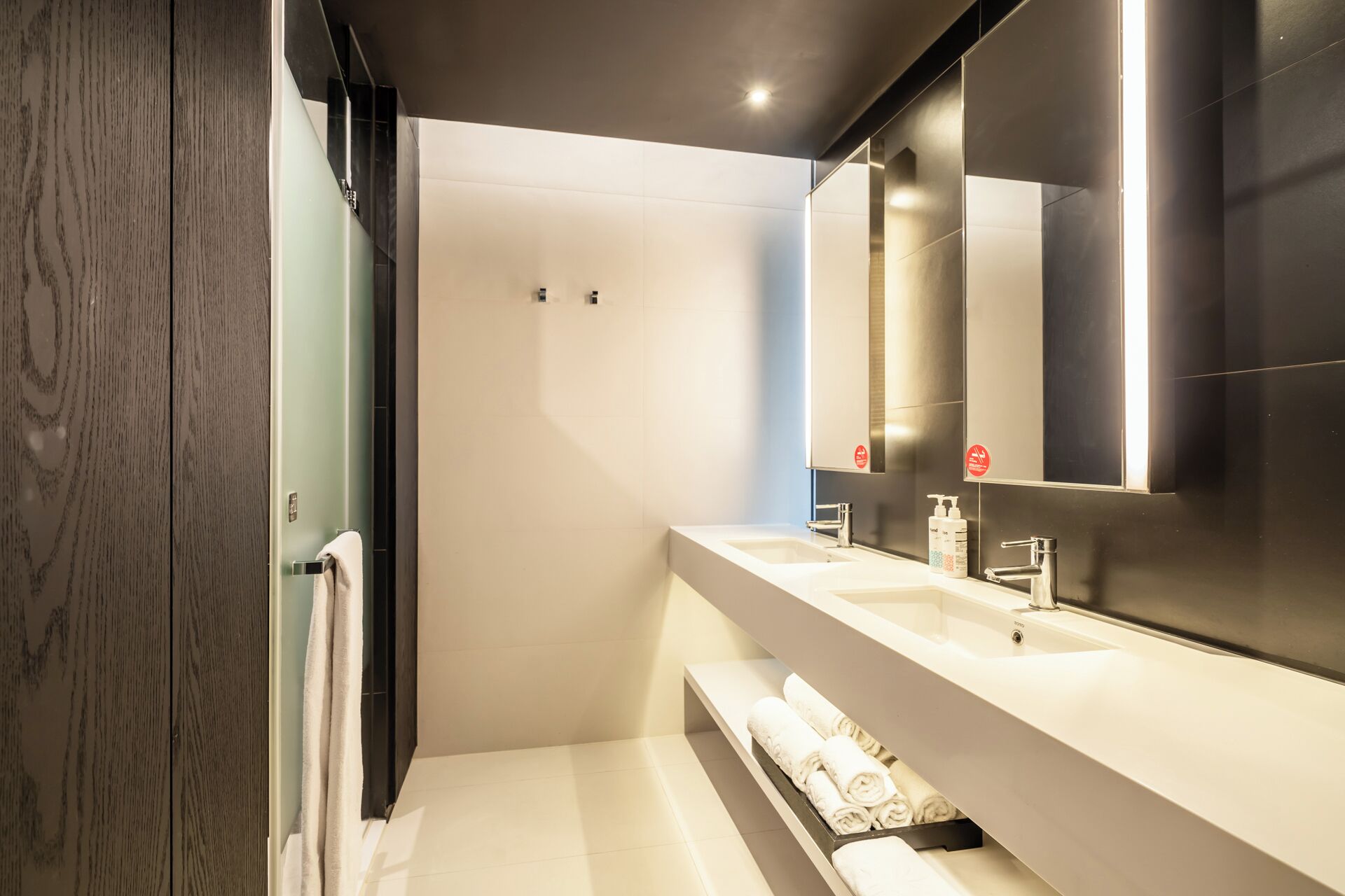 A modern bathroom with a large mirror, two sinks, and a towel rack.