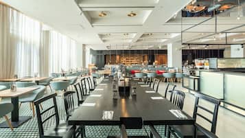 A spacious restaurant with high ceilings, modern lighting, and a mix of seating arrangements including tables and booths.