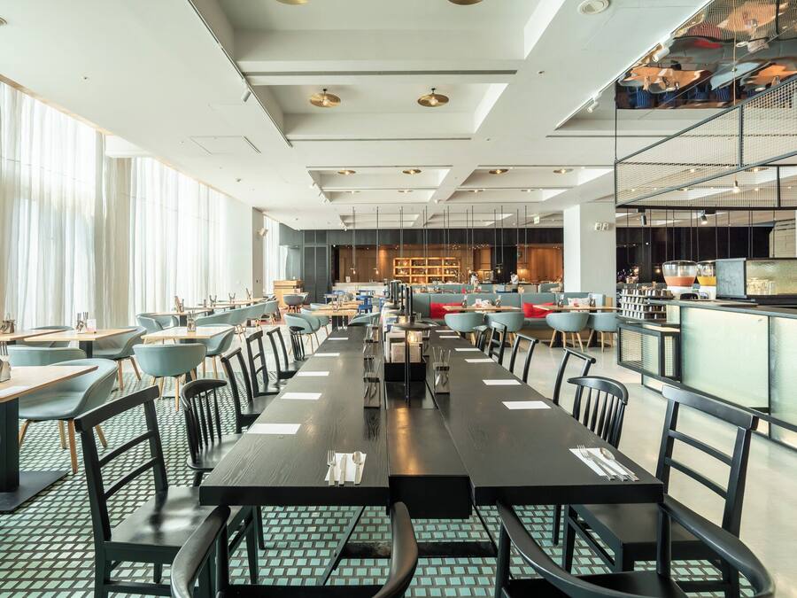 A spacious restaurant with high ceilings, modern lighting, and a mix of seating arrangements including tables and booths.