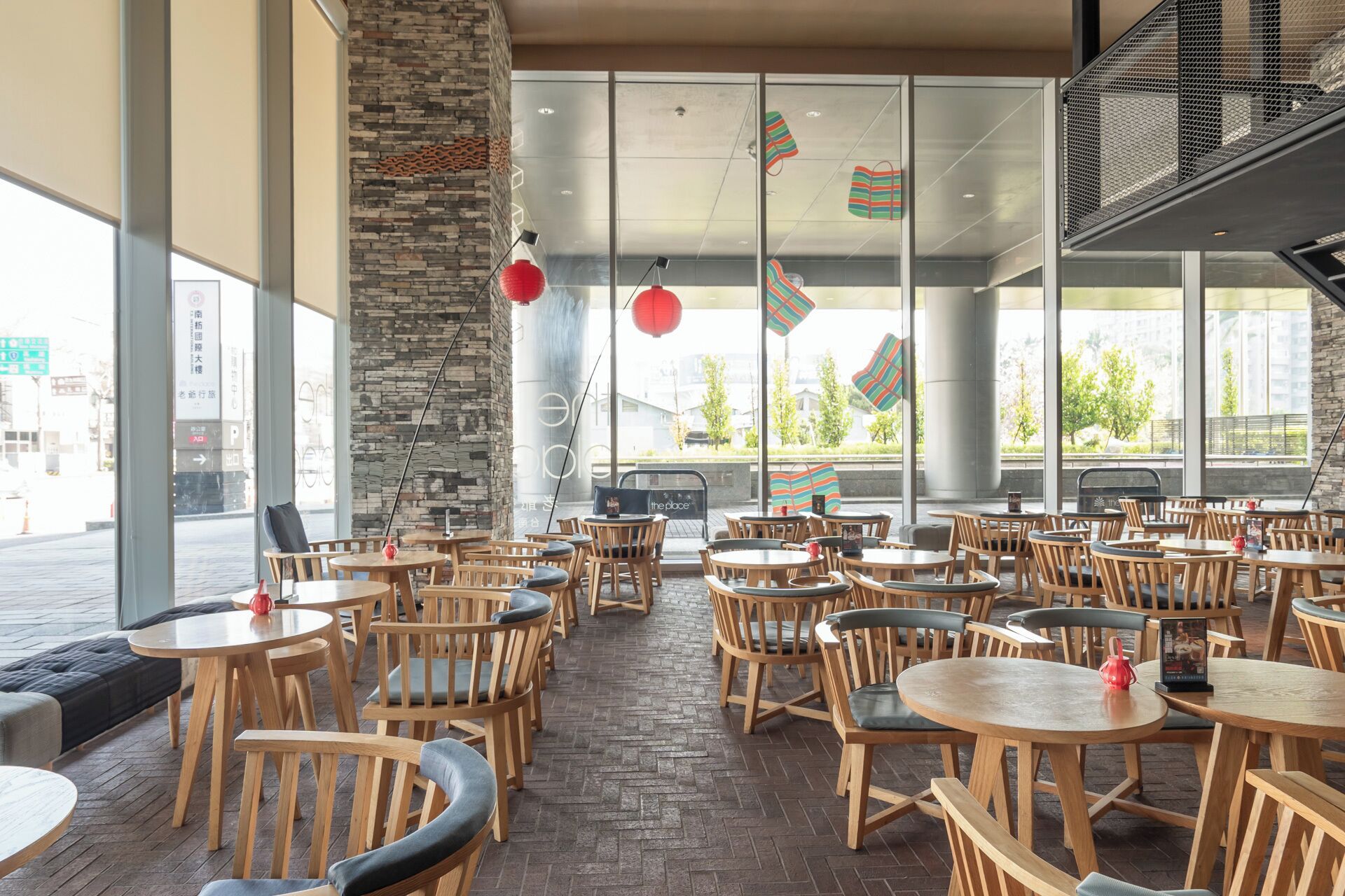 Un restaurant spacieux avec des tables et des chaises en bois, de grandes fenêtres et un mur en pierre.