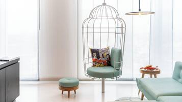 A modern living room with a hanging chair, a small ottoman, and a side table with snacks.