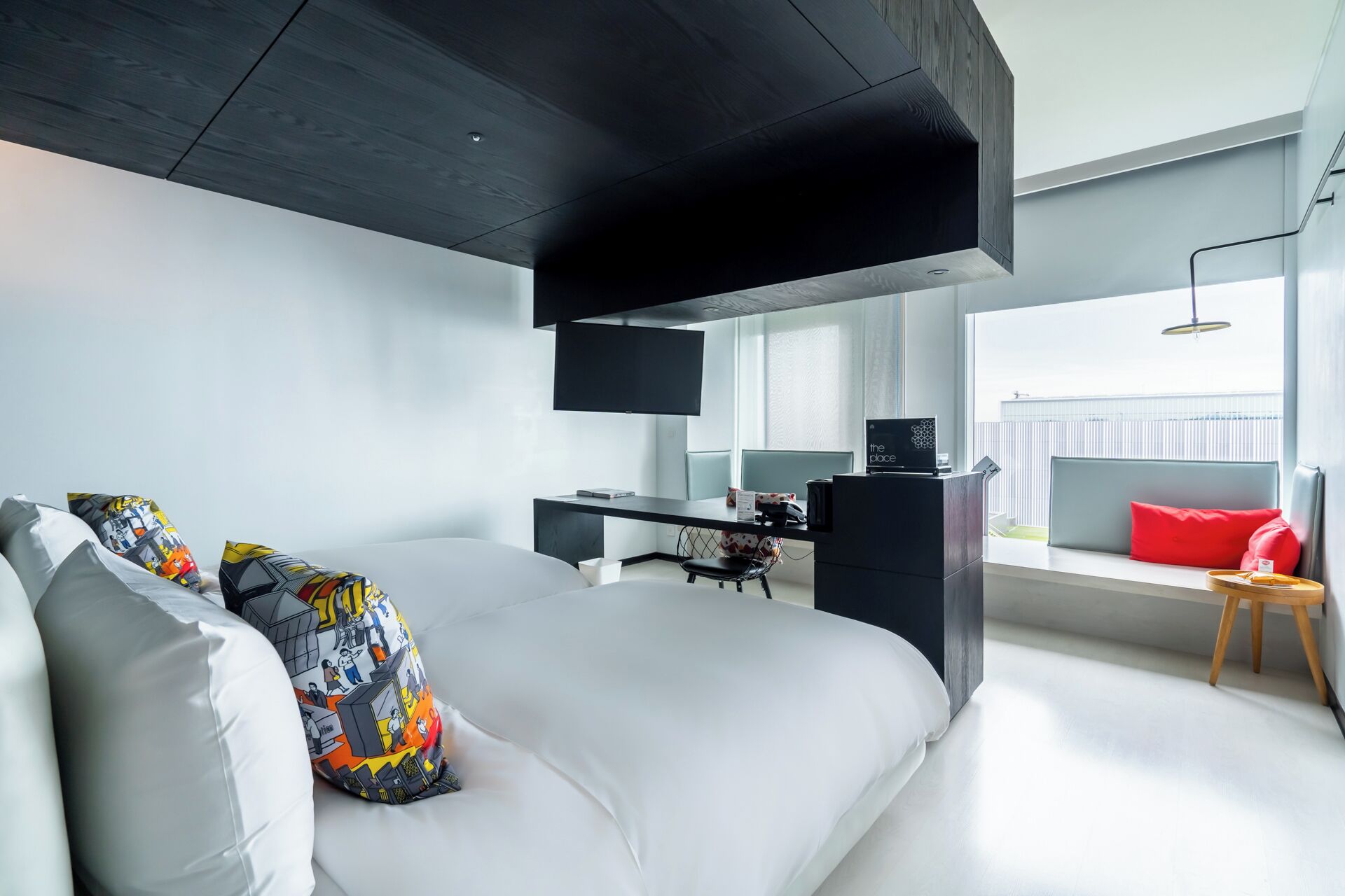 A modern hotel room with a large bed, a desk, and a view of the city.
