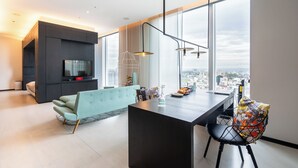 Una sala de estar moderna con un ventanal grande, un sofá, una mesa de comedor y un televisor.