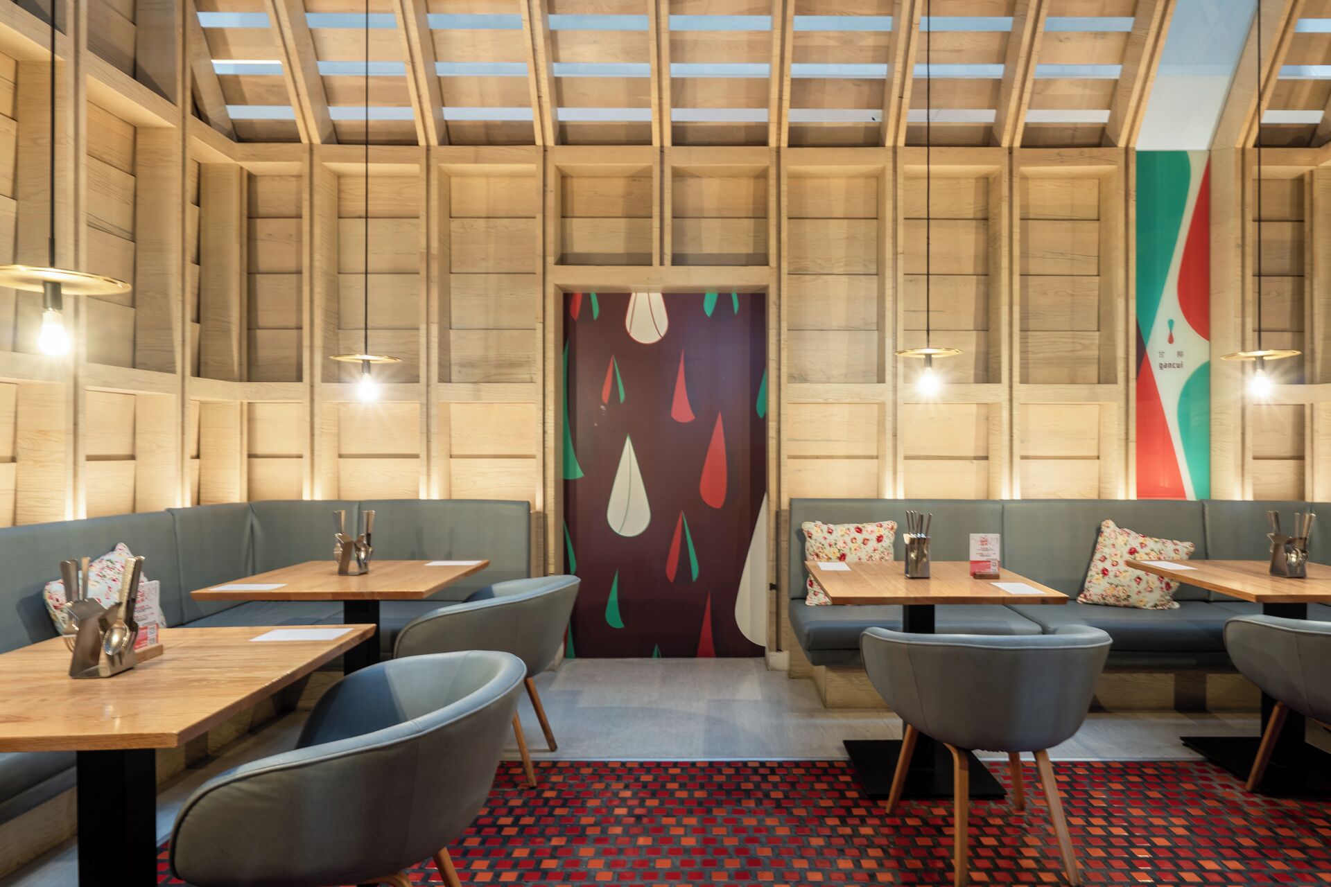 Ein Restaurantinneres mit Holzwandverkleidung, moderner Sitzmöbeln und einer Wanddekoration mit Muster.