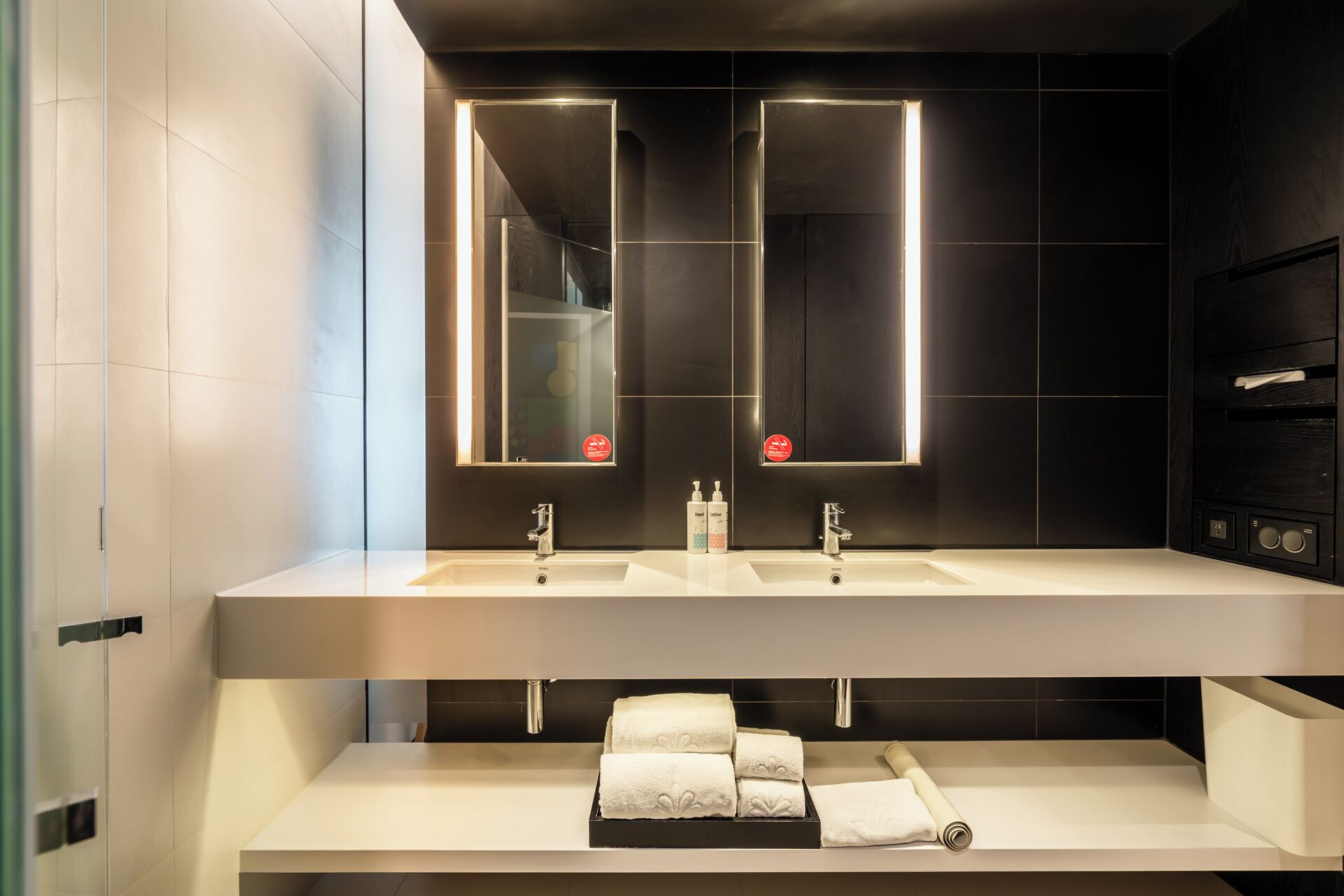 A modern bathroom with two sinks, a mirror, and a towel rack.