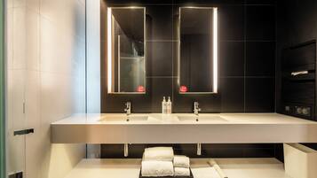 A modern bathroom with two sinks, a mirror, and a towel rack.