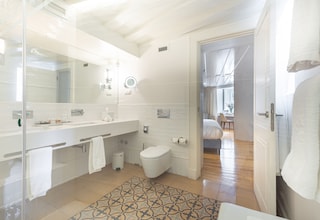A modern bathroom with a glass shower enclosure, a white sink, and a patterned rug.