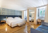 A bedroom with a large bed, a bench, a desk, and a chair.