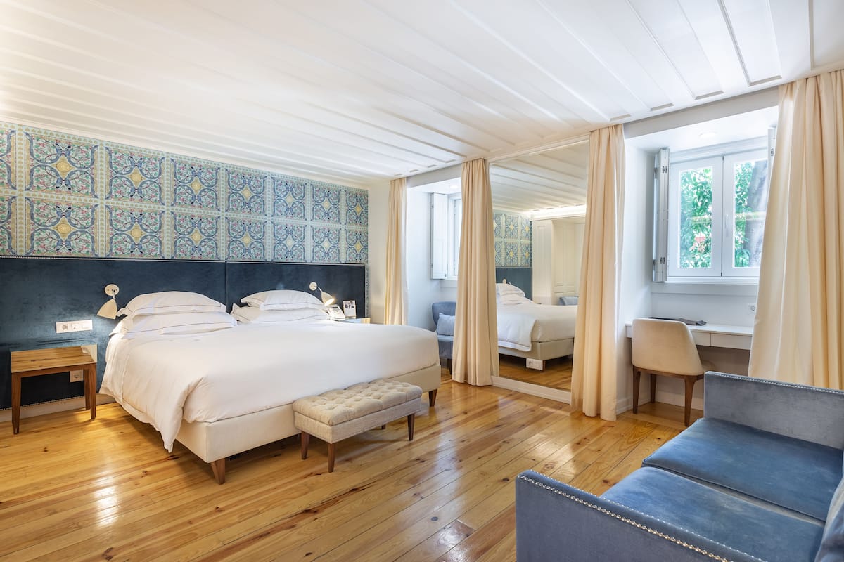 Ein Schlafzimmer mit einem großen Bett, einer Bank, einem Schreibtisch und einem Stuhl.