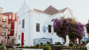 A white building with a red door, a blue mural, and a statue. - Santiago de Alfama - Boutique Hotel (Lisbon)