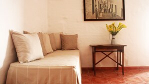 Une pièce avec un lit, une petite table sur laquelle est posé un vase de fleurs et un tableau encadré au mur.