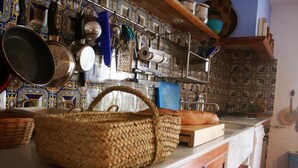 Une cuisine avec un panier tressé posé sur le comptoir, un pare-feu décoré et divers ustensiles de cuisine.