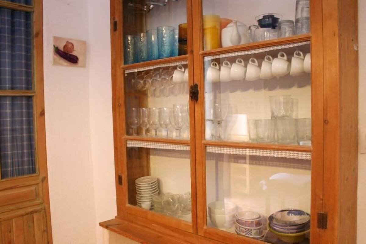 A wooden cabinet with glass doors containing various glassware and dishes.