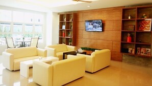 A modern living room with a sofa set, a coffee table, and a flat-screen TV mounted on a wooden wall. - Wealth 30th Apartment (Bangkok)
