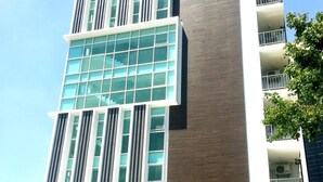 A modern multi-story building with large windows, a flat roof, and a series of balconies. - Wealth 30th Apartment (Bangkok)