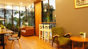 A modern interior with a wooden floor, a sofa, a dining table with chairs, and a large window with a view of the outside. - Wealth 30th Apartment (Bangkok)