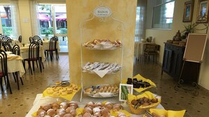 A buffet setup with various pastries and desserts displayed on trays and stands. - Hotel Angela (Misano Adriatico)