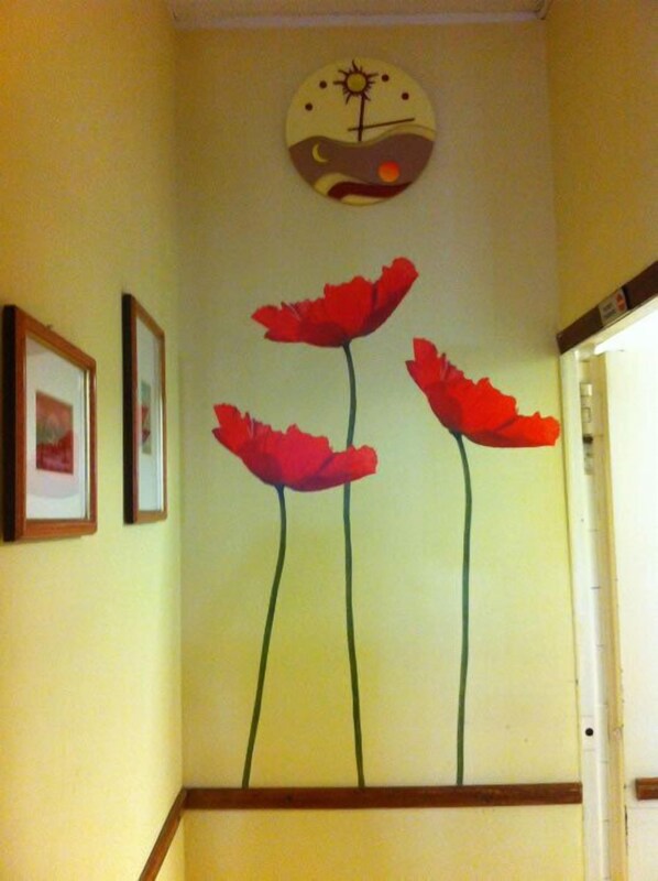 Un pasillo con un reloj en la pared y tres flores rojas.