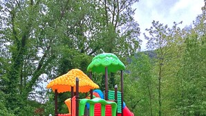 Un parque infantil con un tobogán, estructuras para escalar y una casita en el árbol.