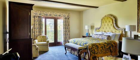 A hotel room with a large bed, a sitting area with a chair, a desk with a lamp, and a view through the window.