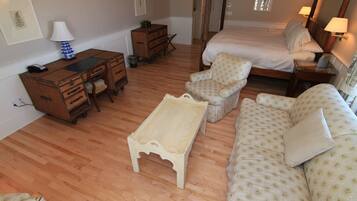 A bedroom with a bed, a desk, a chair, and a sofa.