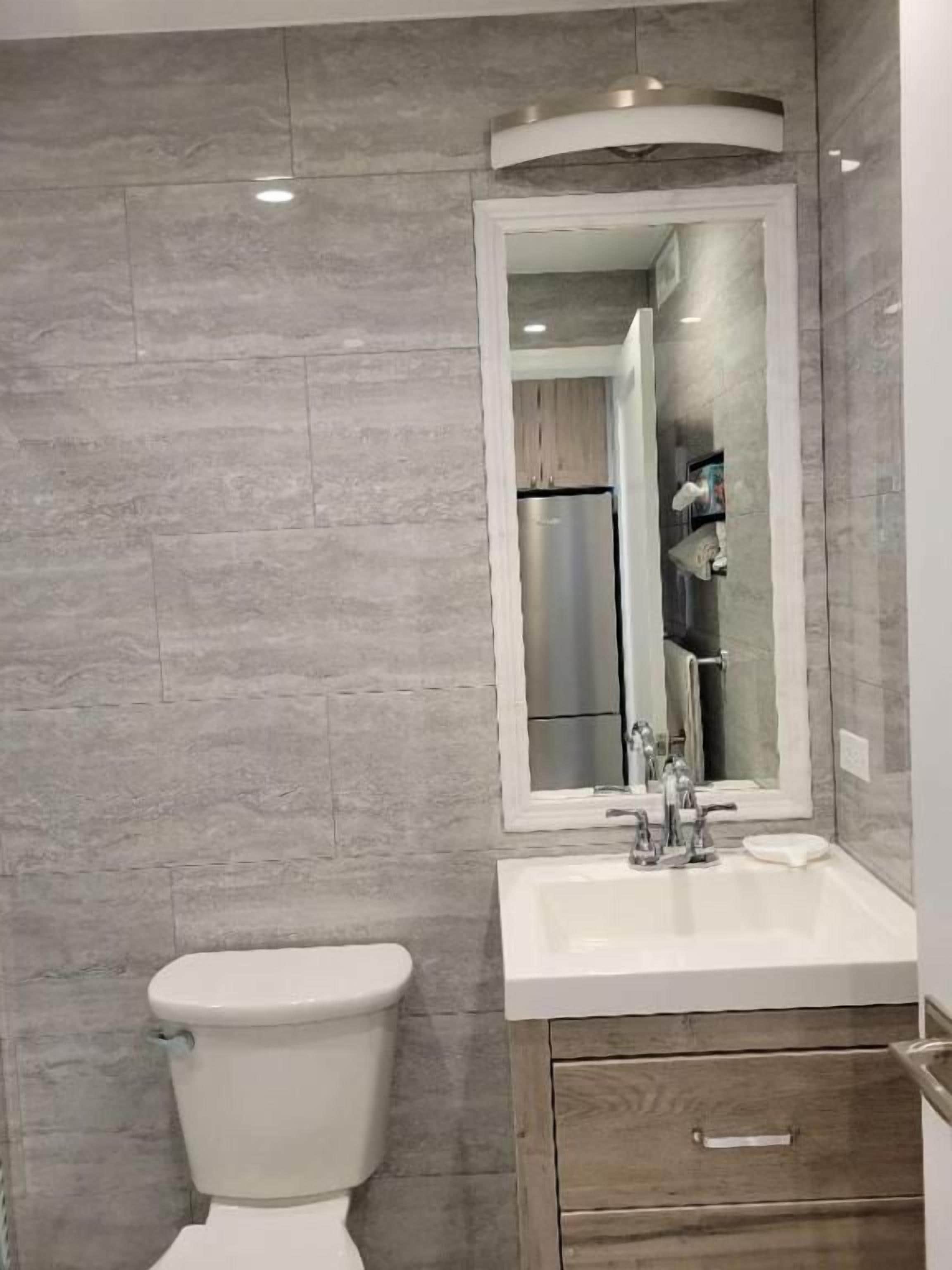 A bathroom with a toilet, sink, and mirror.