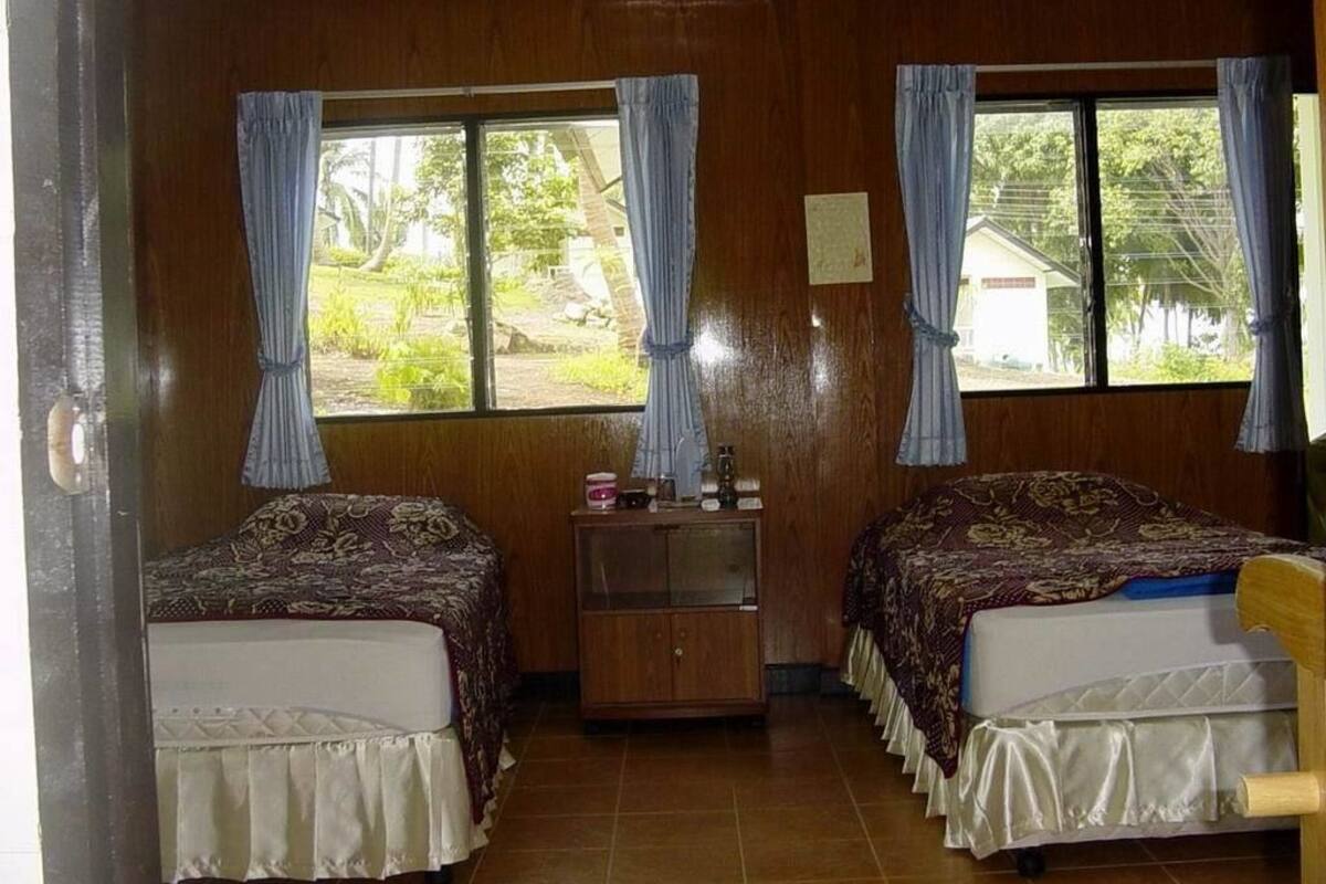 Une chambre avec deux lits, une armoire en bois et une fenêtre avec des rideaux.