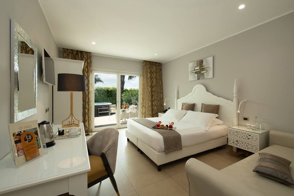 Une chambre d’hôtel moderne dotée d’un grand lit, d’un bureau, d’une chaise, d’une table de chevet et offrant une vue sur l’extérieur.