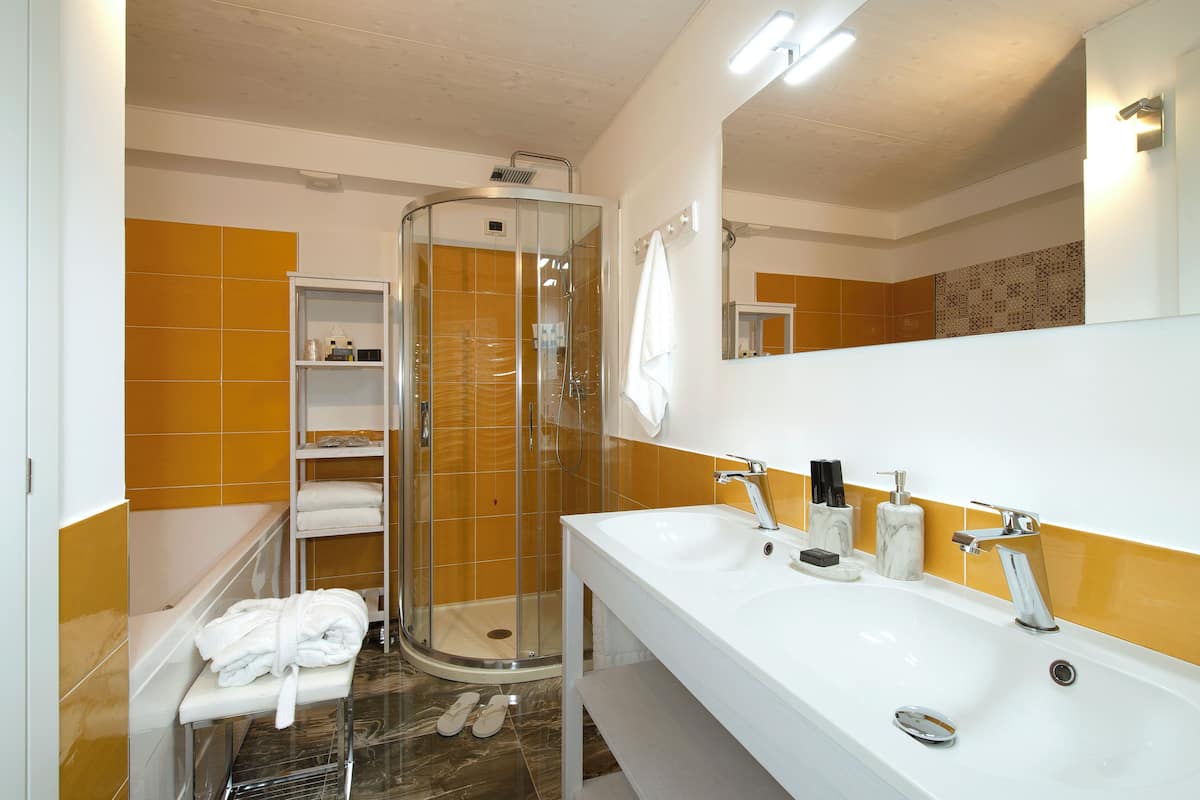 A bathroom with a glass-enclosed shower, a white sink with two faucets, and a mirror above the sink.