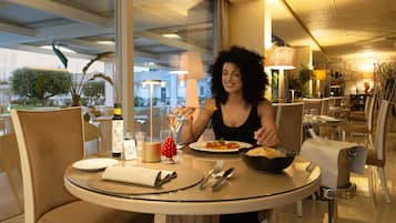 Uma mesa de jantar com uma garrafa de vinho Costa, um copo de água e um prato de comida.