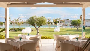 Un espace extérieur aménagé pour les repas, avec des tables et des chaises, une piscine et des palmiers en arrière-plan.