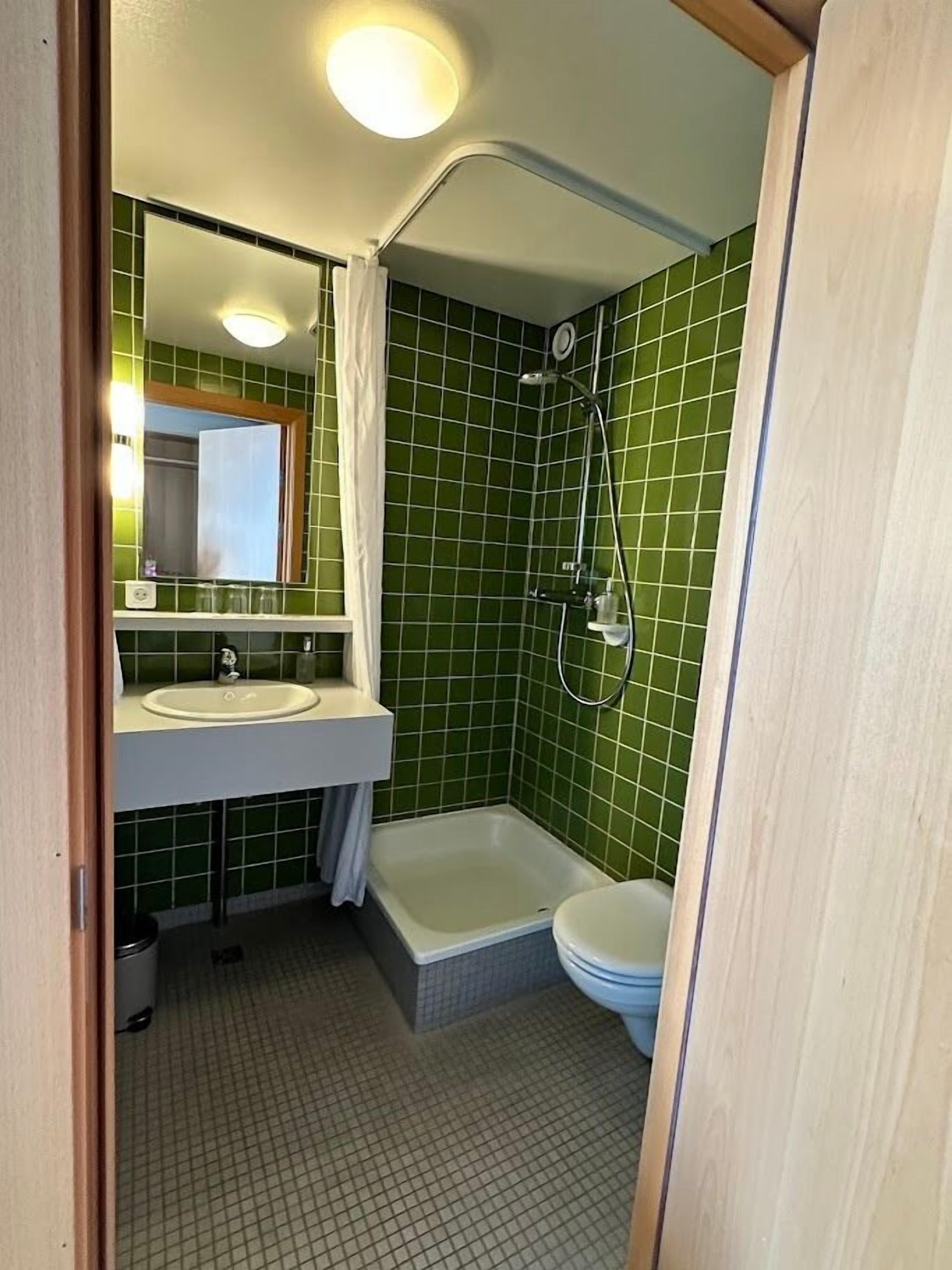 Ein kleines Badezimmer mit Waschbecken, Dusche und Toilette.