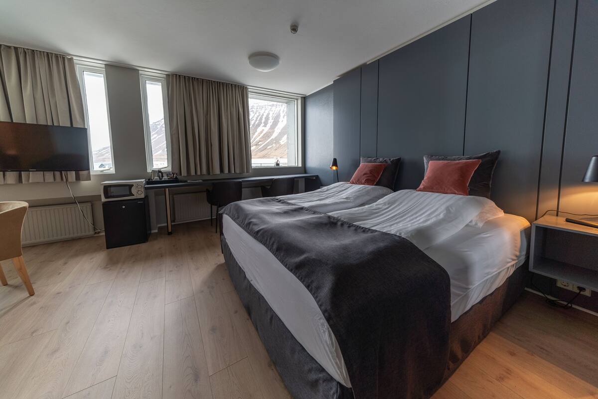 Ein modernes Hotelzimmer mit einem großen Bett, einem Schreibtisch und einem Fernseher.