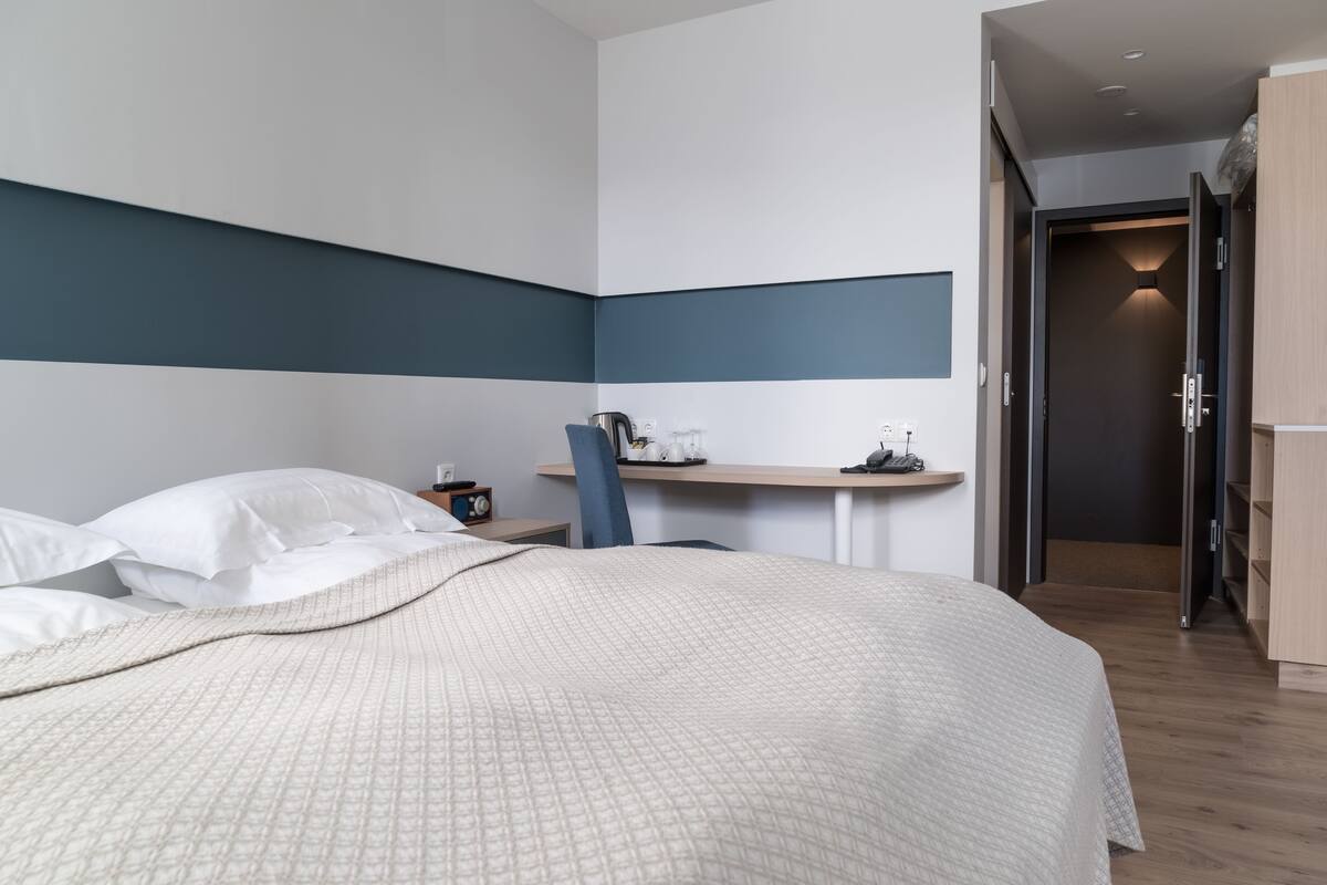Ein modernes Hotelzimmer mit einem großen Bett, einem Schreibtisch und einem Stuhl.